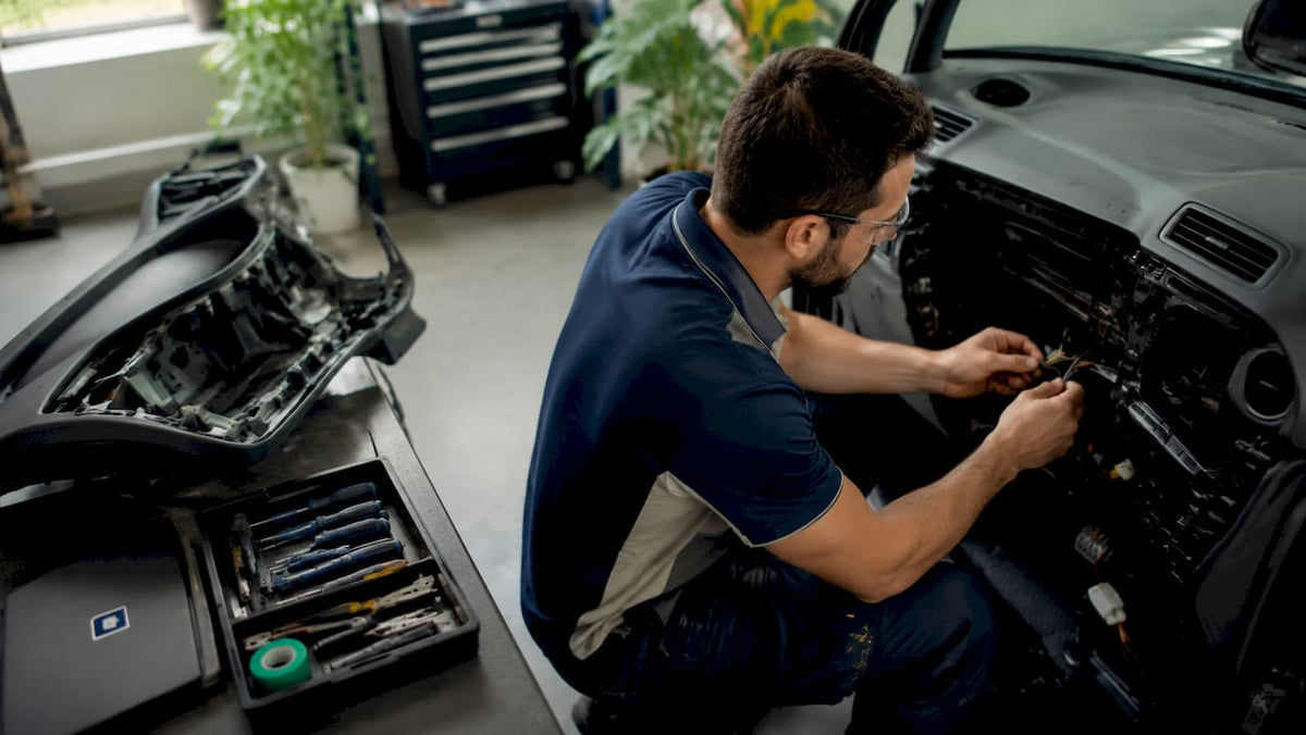 Technician installing GPS tracker in car dashboard
