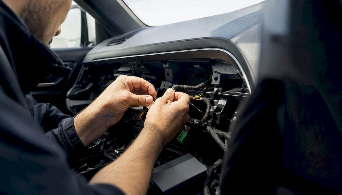 Hands installing vehicle security tracker wiring