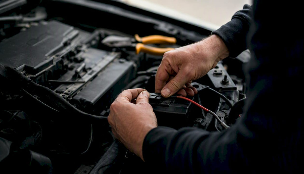 Hands wiring tracker backup battery in vehicle fuse box