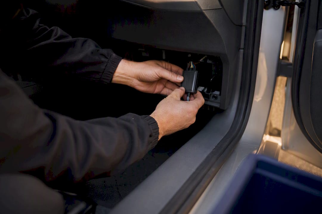 Hands installing tracker inside car glove compartment