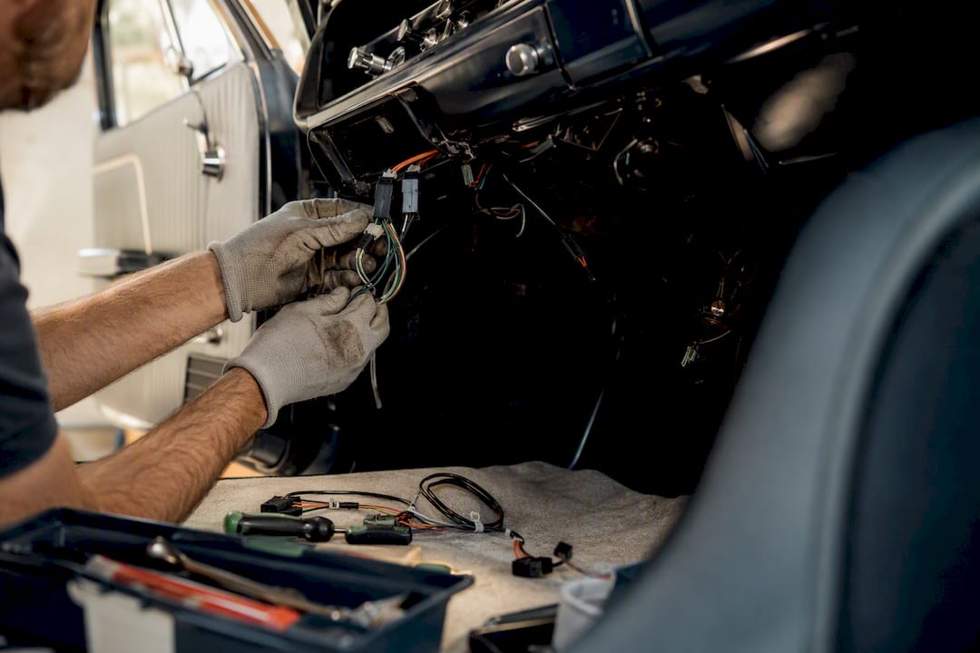 Hands wiring vehicle tracker under dashboard
