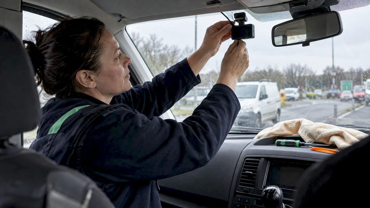 Installer positioning dashcam inside fleet van